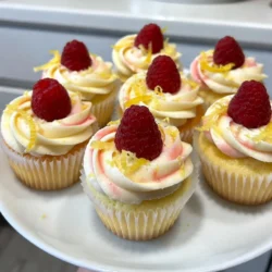 When making Raspberry Lemonade Cupcakes, it's key to gather the right ingredients. Each ingredient plays a role in creating a fresh and flavorful treat. Here&rsquo;s what you need: - 1 &frac12; cups all-purpose flour - 1 cup granulated sugar - 1 &frac12; teaspoons baking powder - &frac12; teaspoon baking soda - &frac14; teaspoon salt - &frac12; cup unsalted butter, softened - 2 large eggs - 1 tablespoon lemon zest - &frac12; cup freshly squeezed lemon juice - &frac12; cup buttermilk - 1 cup fresh raspberries - 1 cup powdered sugar (for frosting) - 2 tablespoons lemon juice (for frosting) - 1 tablespoon lemon zest (for frosting) - 1 tablespoon raspberry puree (optional, for swirl) Each item contributes its own flavor. The flour gives structure. The sugar adds sweetness. The baking powder and baking soda help the cupcakes rise. Fresh raspberries provide juicy bursts of flavor. Lemon juice and zest bring brightness. For the frosting, the powdered sugar makes it sweet and creamy. The extra lemon juice and zest enhance the frosting's tang. If you want a fun twist, use raspberry puree to create a beautiful swirl. Having all these ingredients ready makes the process smooth and fun. Enjoy the journey of baking these delightful cupcakes! {{ingredient_image_2}} First, set your oven to 350&deg;F (175&deg;C). This step preps your oven for even baking. Next, grab a 12-cup muffin tin. Line it with fun cupcake liners to make your treats pop. In a medium bowl, whisk together 1 &frac12; cups all-purpose flour, 1 &frac12; teaspoons baking powder, &frac12; teaspoon baking soda, and &frac14; teaspoon salt. This mix helps your cupcakes rise well. Set it aside for later. In a large bowl, cream together &frac12; cup softened unsalted butter and 1 cup granulated sugar. Use an electric mixer on medium speed. Beat this for about 3 to 4 minutes. You want it to be light and fluffy. This step adds air, making your cupcakes soft. Now, add 2 large eggs, one at a time. Mix well after each egg. Then stir in 1 tablespoon of fresh lemon zest and &frac12; cup of freshly squeezed lemon juice. This adds a bright flavor to your batter. Gradually mix in the dry ingredients you set aside. Alternate this with &frac12; cup of buttermilk. Start with a third of the dry mix, then half the buttermilk. Repeat this until you finish with the dry mix. Mix just until combined to keep your cupcakes light. Gently fold in 1 cup of fresh raspberries. Use a spatula and be careful not to mash them. You want those juicy bursts in every bite. Fill each cupcake liner about two-thirds full with the batter. This gives them room to rise. Place the muffin tin in the preheated oven. Bake for 18 to 20 minutes. Use a toothpick to check; it should come out clean. Let them cool in the pan for 5 minutes before moving to a wire rack. In a medium bowl, beat softened butter until smooth. Gradually mix in 1 cup of powdered sugar, 2 tablespoons of lemon juice, and 1 tablespoon of lemon zest. Blend until creamy. If you need to, add more lemon juice to adjust the texture. Once your cupcakes are cool, use a piping bag with a star tip. Frost each cupcake generously for a lovely finish. For a fun twist, mix a bit of raspberry puree into some frosting to create a swirl effect. Top each cupcake with a few fresh raspberries and a sprinkle of lemon zest for that extra zing. To bake perfect Raspberry Lemonade Cupcakes, follow these tips: - Measure Accurately: Use the right measuring cups for dry and wet ingredients. This ensures your batter has the right texture. - Room Temperature Ingredients: Make sure your butter and eggs are at room temperature. This helps them blend well. - Oven Temperature Check: Always preheat your oven. An oven thermometer can help you avoid temperature issues. Fluffy cupcakes are a joy. Here are some ways to achieve that: - Cream Butter and Sugar Well: Beat the butter and sugar for 3-4 minutes. This adds air to the batter. - Don&rsquo;t Overmix: Mix your batter just until combined. Overmixing can lead to dense cupcakes. - Use Fresh Ingredients: Fresh eggs and lemon juice make a big difference in taste and texture. Frosting can make or break your cupcake. Here&rsquo;s how to make it great: - Softened Butter: Use softened butter for a smooth mix. Cold butter can lead to lumps. - Gradual Sugar Addition: Add powdered sugar slowly. This helps you control the consistency. - Taste as You Go: Always taste your frosting. Adjust lemon juice or sugar for your perfect flavor. If you have cupcakes left, store them right: - Cool Completely: Let the cupcakes cool fully before storing. This prevents sogginess. - Airtight Containers: Use airtight containers to keep them fresh. Line with parchment paper if you want to avoid sticking. - Refrigerate or Freeze: For longer storage, refrigerate for up to a week or freeze for up to three months. Pro Tips Use Fresh Raspberries: Fresh raspberries will provide the best flavor and texture. If using frozen, make sure to thaw and drain them well to avoid excess moisture in the batter. Room Temperature Ingredients: Ensure your butter and eggs are at room temperature for better incorporation, leading to a lighter and fluffier cupcake. Don&rsquo;t Overmix the Batter: Mix until just combined when adding the dry ingredients to avoid tough cupcakes. A few lumps are perfectly fine! Decorating with Style: For a professional look, use a piping bag to frost your cupcakes. Experiment with different tips to create unique designs! {{image_4}} You can easily change the flavor of these cupcakes. Instead of raspberries, try blueberries or strawberries. Both fruits add a sweet taste. You can also switch the lemon juice for lime juice. This gives a fun twist to the classic recipe. To make these cupcakes gluten-free, use a gluten-free flour blend. Look for a blend that works well in baking. Make sure it has a good mix of flours. This helps keep the texture light and fluffy. You might also want to add a bit of xanthan gum to help bind the ingredients. If you need a dairy-free version, swap the butter for coconut oil. Use almond milk or oat milk instead of buttermilk. These options keep the cupcakes moist and delicious. Just be mindful of the flavor, as coconut oil can add a slight taste. Get creative with your cupcake toppings! Instead of the lemon frosting, use a cream cheese frosting for a richer taste. You can also add a sprinkle of crushed nuts on top. For a fun look, use colorful sprinkles or edible flowers. Each topping brings a new twist to your raspberry lemonade cupcakes. To keep your Raspberry Lemonade Cupcakes fresh, store them in an airtight container. This helps keep moisture in and prevents them from drying out. Line the container with a paper towel before placing the cupcakes inside. This absorbs any excess moisture. You can store them at room temperature for up to three days. If you want them to last longer, refrigerate them. Just remember, refrigeration can change the texture slightly. You can freeze these cupcakes if you want to save some for later. First, let the cupcakes cool completely. Then, wrap each cupcake tightly in plastic wrap. After that, place them in a freezer-safe bag. This prevents freezer burn and keeps them fresh. They can stay in the freezer for up to three months. When you're ready to enjoy them, simply thaw them at room temperature. If you like, frost them after thawing for the best taste. The shelf life of these cupcakes varies based on storage. At room temperature, they last 2-3 days. If stored in the fridge, they can stay fresh for about a week. Freezing extends their life to three months. Always check for changes in smell or texture before eating. Your cupcakes should stay moist and flavorful, so proper storage is key for the best taste. To make raspberry puree, blend fresh raspberries in a blender or food processor. Puree until smooth. If you want a smoother texture, strain it through a fine mesh to remove seeds. This puree adds a burst of flavor to your cupcakes or frosting. Yes, you can use frozen raspberries. Thaw them first and drain excess liquid. This helps prevent the batter from becoming too wet. The flavor remains strong, and they work well in the recipe. To ensure even baking, place your cupcake tin in the center of the oven. This allows for even heat flow. Rotate the tin halfway through baking for consistent results. You can customize the frosting by adding different flavors or colors. Mix in fruit purees or extracts like vanilla or almond. For a fun twist, add a touch of food coloring for a pop of color. You can make these cupcakes a day ahead. Bake and cool them completely. Store them in an airtight container at room temperature. Frost them just before serving for the best taste and look. You now know how to make delicious raspberry lemon cupcakes from scratch. We reviewed key ingredients, simple steps, and helpful tips. Experiment with various flavors and adapt the recipe to fit your needs. Always store your treats properly for the best freshness. Enjoy creating these sweet delights while sharing them with friends and family. Happy baking!